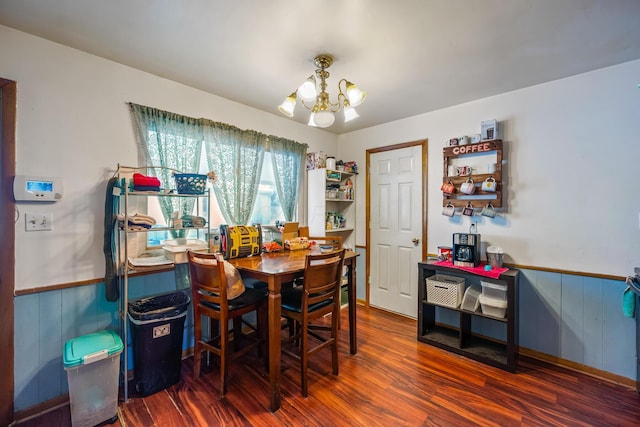 dining room featuring a notable chandelier, wooden walls, and dark hardwood / wood-style floors