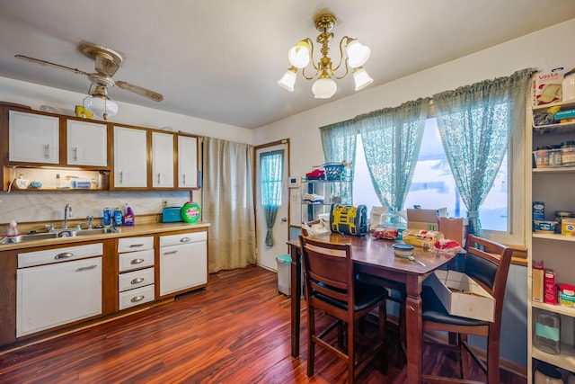 dining area with dark hardwood / wood-style flooring, sink, and ceiling fan with notable chandelier