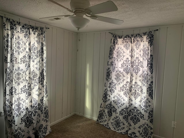 carpeted empty room featuring ceiling fan and a textured ceiling