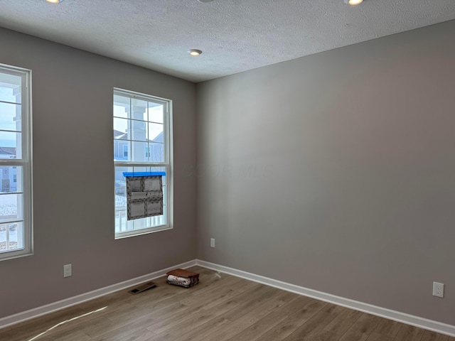 unfurnished room featuring wood-type flooring and a textured ceiling