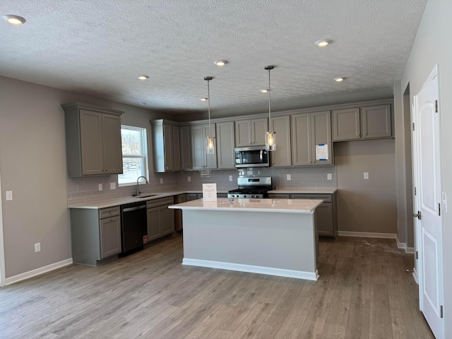 kitchen featuring appliances with stainless steel finishes, hanging light fixtures, gray cabinetry, and a center island