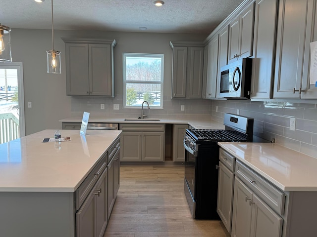 kitchen featuring gray cabinets, light hardwood / wood-style floors, gas stove, and sink