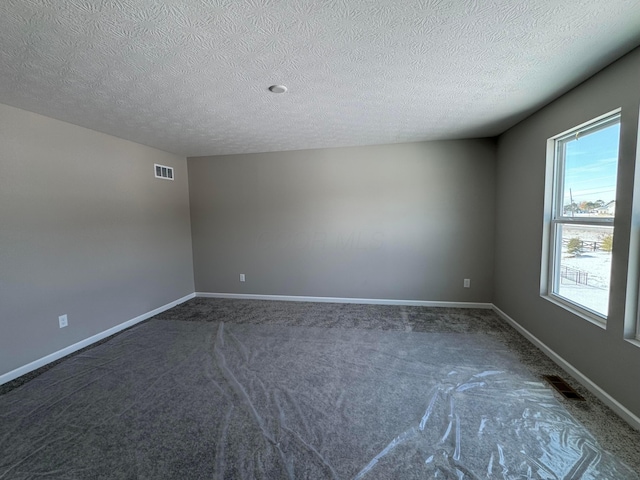 empty room with dark carpet and a textured ceiling