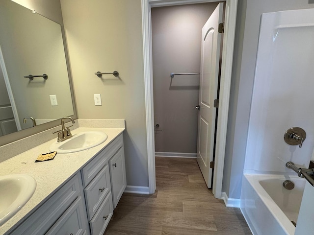 bathroom with hardwood / wood-style flooring, vanity, and bathing tub / shower combination