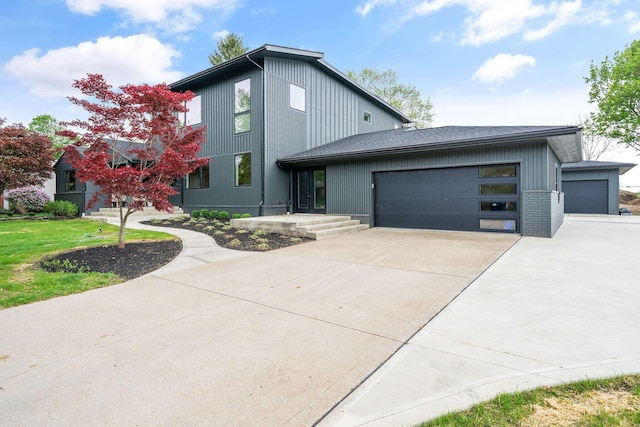 contemporary house with an attached garage, a shingled roof, and driveway