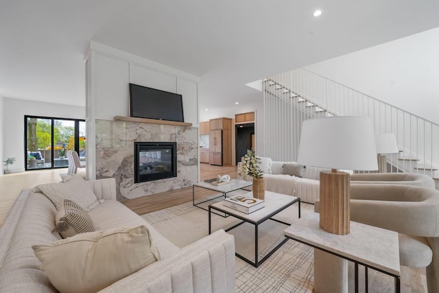 living room featuring recessed lighting, stairway, light wood-style flooring, and a high end fireplace