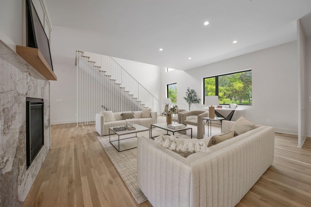 living area featuring light wood-style flooring, baseboards, recessed lighting, and a tile fireplace