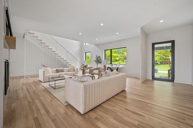 living area featuring baseboards, stairs, light wood-style flooring, and recessed lighting