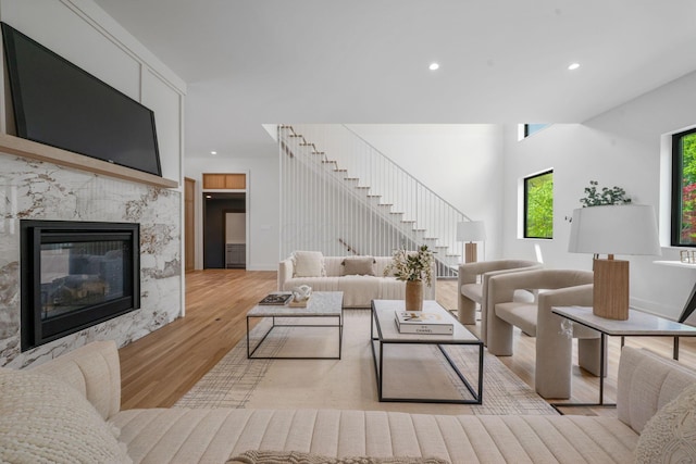 living area featuring stairway, recessed lighting, a premium fireplace, and wood finished floors