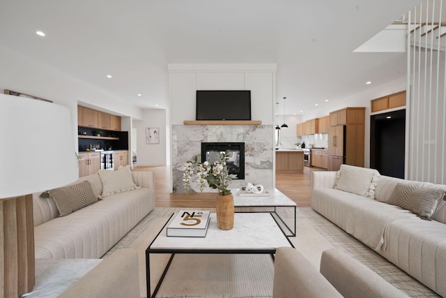 living room with recessed lighting, a high end fireplace, and light wood-type flooring