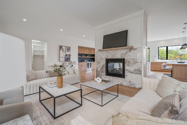 living room with a premium fireplace, built in features, recessed lighting, and light wood-style floors
