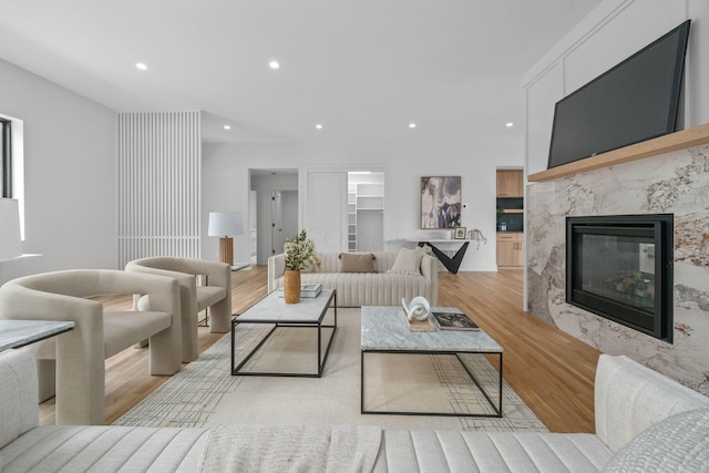 living area with recessed lighting, a fireplace, light wood-type flooring, and built in features