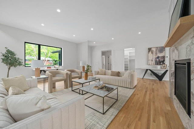 living area featuring a premium fireplace, recessed lighting, and light wood-style floors