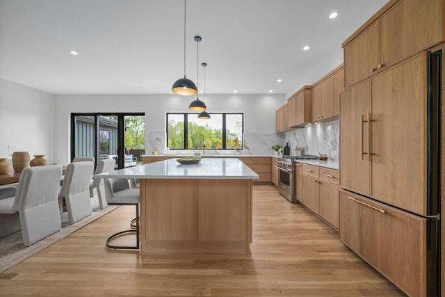 kitchen featuring tasteful backsplash, high quality appliances, a center island, light countertops, and light wood-style floors