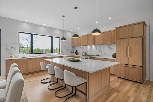 kitchen featuring paneled built in refrigerator, tasteful backsplash, light wood-type flooring, and a kitchen island