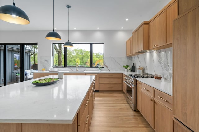 kitchen with a center island, paneled built in refrigerator, a sink, high end stainless steel range, and light wood-type flooring