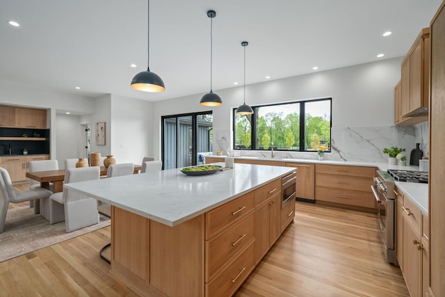 kitchen with light wood finished floors, a center island, a kitchen bar, backsplash, and appliances with stainless steel finishes