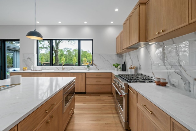kitchen featuring a sink, light wood-type flooring, light stone countertops, appliances with stainless steel finishes, and recessed lighting