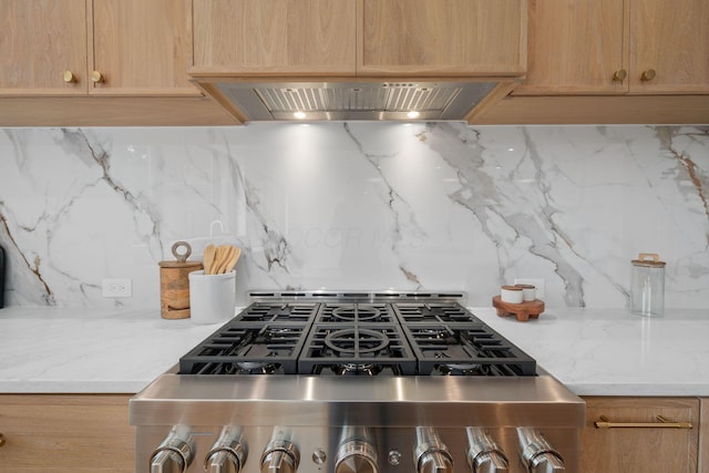 kitchen featuring light stone counters, wall chimney exhaust hood, and decorative backsplash