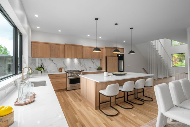 kitchen with a sink, high end stainless steel range, recessed lighting, light countertops, and a kitchen island