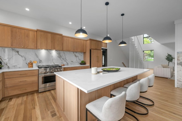 kitchen featuring a center island, light wood-style flooring, high end range, light countertops, and tasteful backsplash