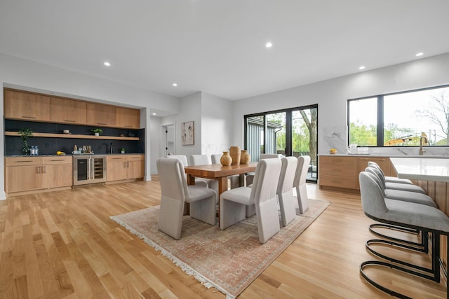 dining space with beverage cooler, indoor wet bar, light wood-style flooring, and recessed lighting