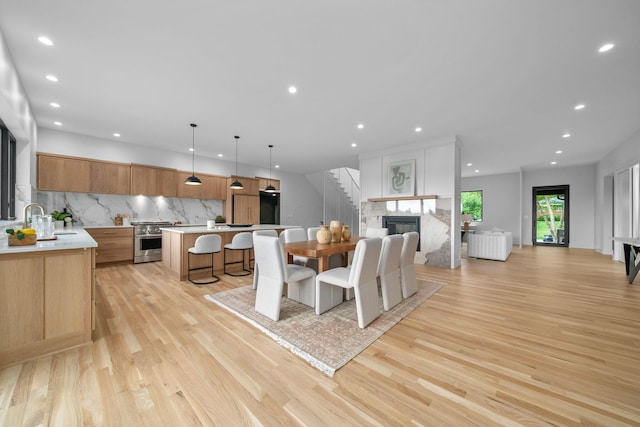 dining space featuring light wood-style floors, a multi sided fireplace, stairs, and recessed lighting