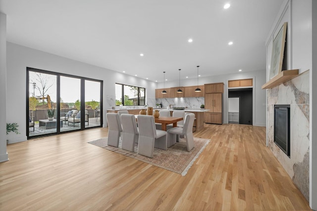dining room featuring a tile fireplace, light wood-type flooring, and recessed lighting
