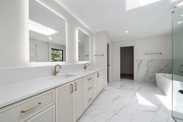 full bathroom featuring a sink, a freestanding bath, a skylight, and double vanity