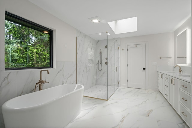 bathroom featuring marble finish floor, vanity, a freestanding tub, a marble finish shower, and a skylight