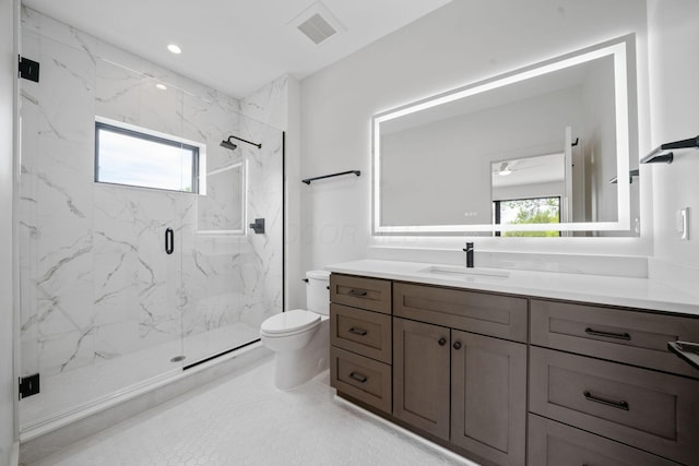 bathroom with toilet, vanity, a marble finish shower, visible vents, and a ceiling fan