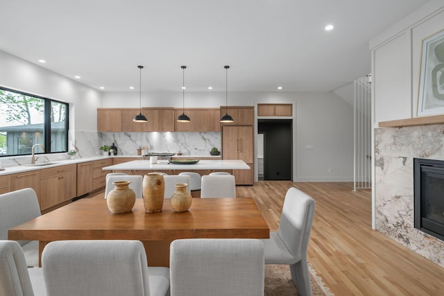 dining room featuring light wood finished floors, a high end fireplace, and recessed lighting