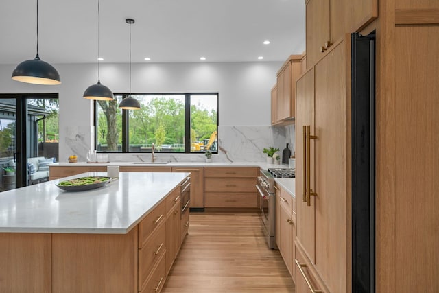 kitchen featuring recessed lighting, stainless steel stove, decorative backsplash, a kitchen island, and light wood-type flooring