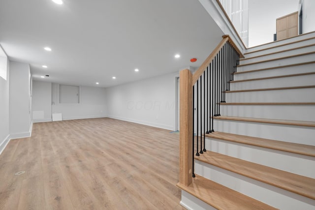 staircase featuring wood finished floors, baseboards, and recessed lighting