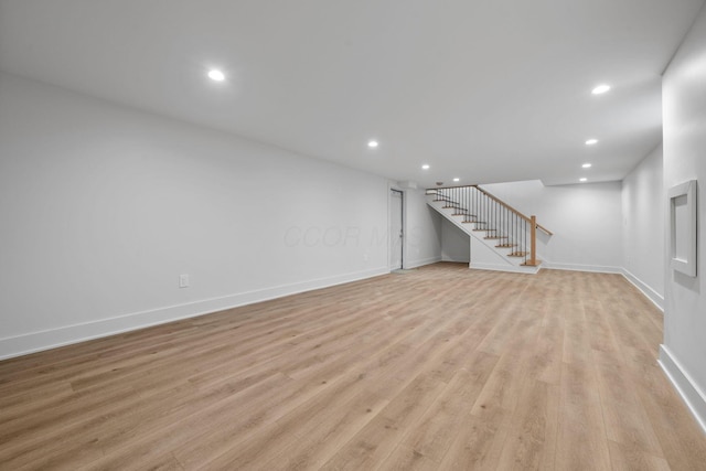 finished basement with baseboards, stairway, recessed lighting, and light wood-style floors