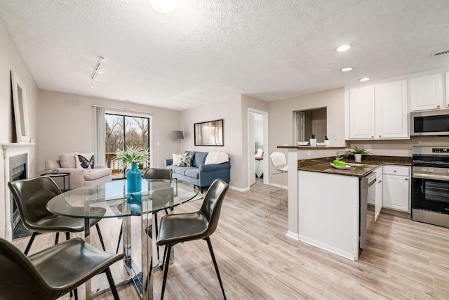 dining area featuring light hardwood / wood-style floors, rail lighting, and a textured ceiling