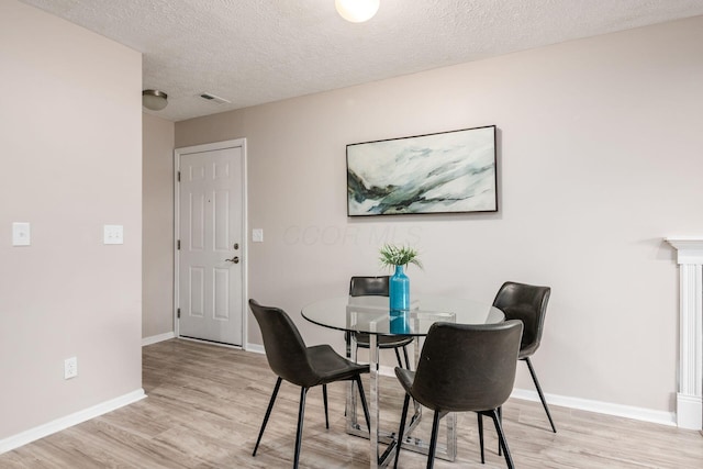 dining area with light hardwood / wood-style flooring and a textured ceiling