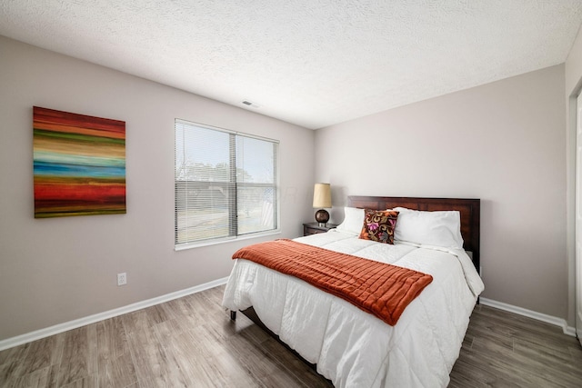 bedroom featuring hardwood / wood-style floors and a textured ceiling