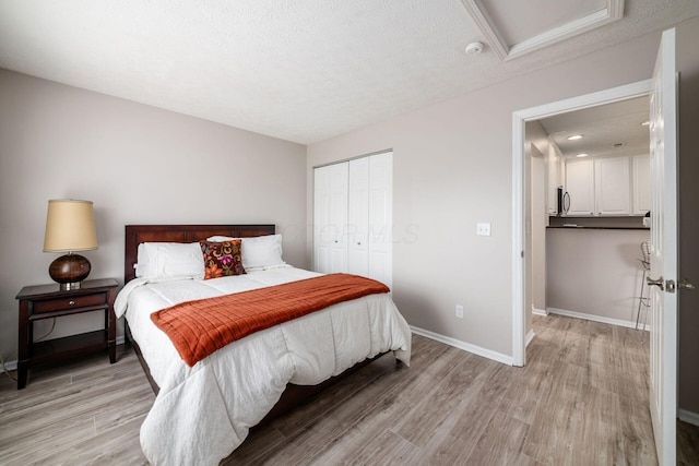 bedroom featuring a closet, light hardwood / wood-style flooring, and a textured ceiling