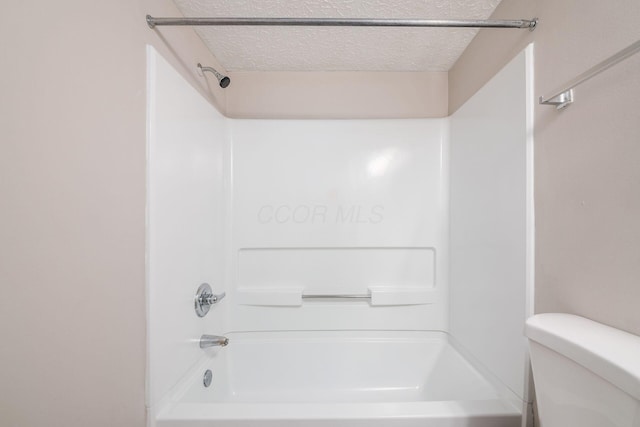 bathroom with toilet, shower / bathing tub combination, and a textured ceiling