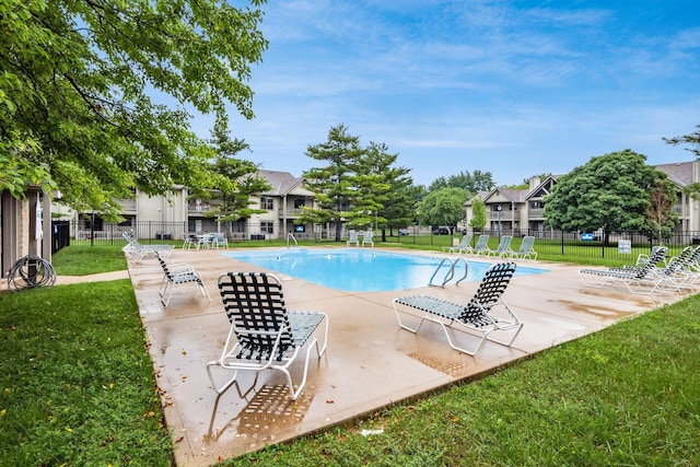 view of pool with a patio and a lawn