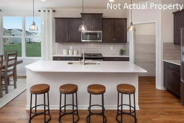 kitchen with dark brown cabinetry, stainless steel microwave, dark wood-style floors, and a sink