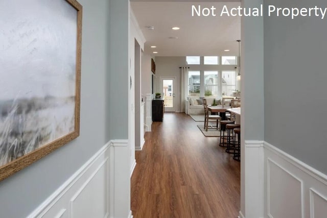 corridor featuring a decorative wall, recessed lighting, dark wood-type flooring, and a wainscoted wall