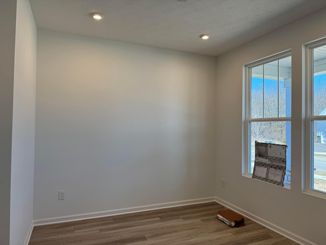 spare room featuring recessed lighting, a textured ceiling, baseboards, and wood finished floors