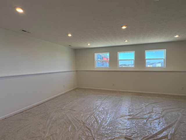 empty room featuring visible vents, recessed lighting, a textured ceiling, and baseboards