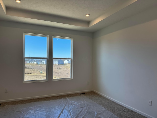 carpeted spare room with a tray ceiling, recessed lighting, baseboards, and a textured ceiling