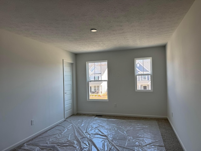 unfurnished room with light carpet, baseboards, and a textured ceiling