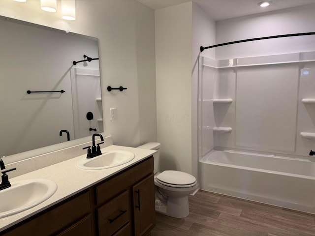 full bathroom with double vanity, toilet, wood finished floors, and a sink