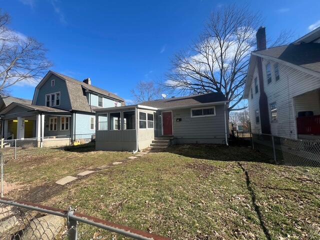 rear view of house featuring a lawn and a sunroom