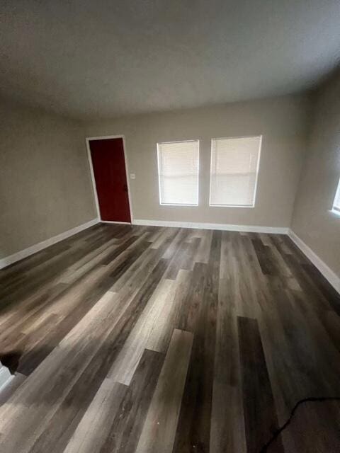 unfurnished living room featuring plenty of natural light and dark wood-type flooring